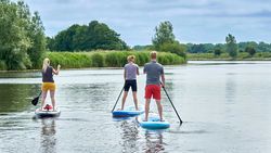 3 Personen von hinten auf SUPs auf der Eider
