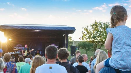 Publikum von hinten vor einer Open-Air-Bühne am Deich