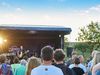 Publikum von hinten vor einer Open-Air-Bühne am Deich